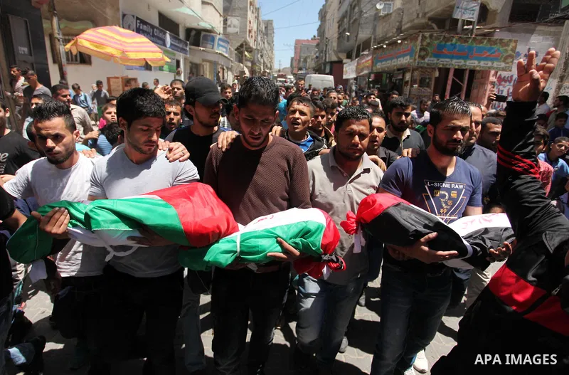 Palestinians carry the bodies of three children from the Abu Hindi family, who died in a fire caused by a candle at the family home, during their funeral at the al-Shati refugee camp in Gaza City on May 7, 2016. Photo by...