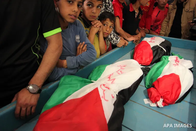 Palestinian children mourn next to the bodies of three boys from the al-Hindi family, who died in a fire caused by a candle at the family home, during their funeral at the al-Shati refugee camp in Gaza City on May 7, 201...