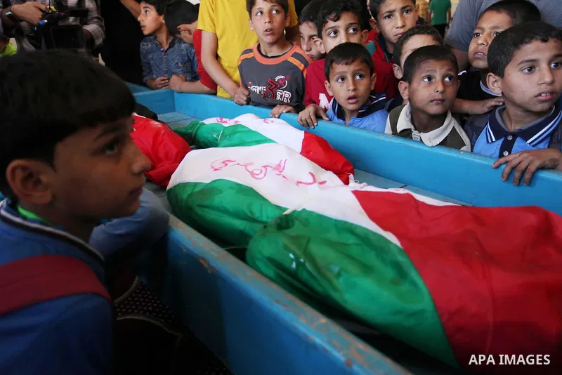 Palestinian children mourn next to the bodies of three boys from the al-Hindi family, who died in a fire caused by a candle at the family home, during their funeral at the al-Shati refugee camp in Gaza City on May 7, 201...