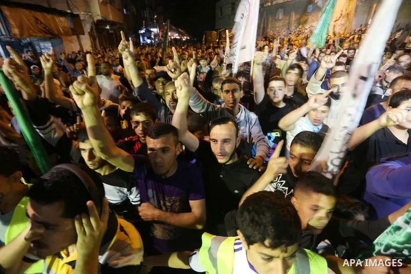 Palestinians hold placards in a protest demanding for end the siege on Gaza and against the killing of three boys from the al-Hindi family, who died in a fire caused by a candle at the family home, in Jabalia in the nort...
