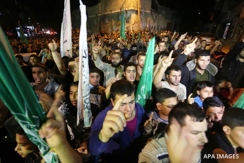 Palestinians hold placards in a protest demanding for end the siege on Gaza and against the killing of three boys from the al-Hindi family, who died in a fire caused by a candle at the family home, in Jabalia in the nort...