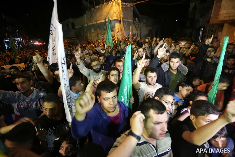 Palestinians hold placards in a protest demanding for end the siege on Gaza and against the killing of three boys from the al-Hindi family, who died in a fire caused by a candle at the family home, in Jabalia in the nort...