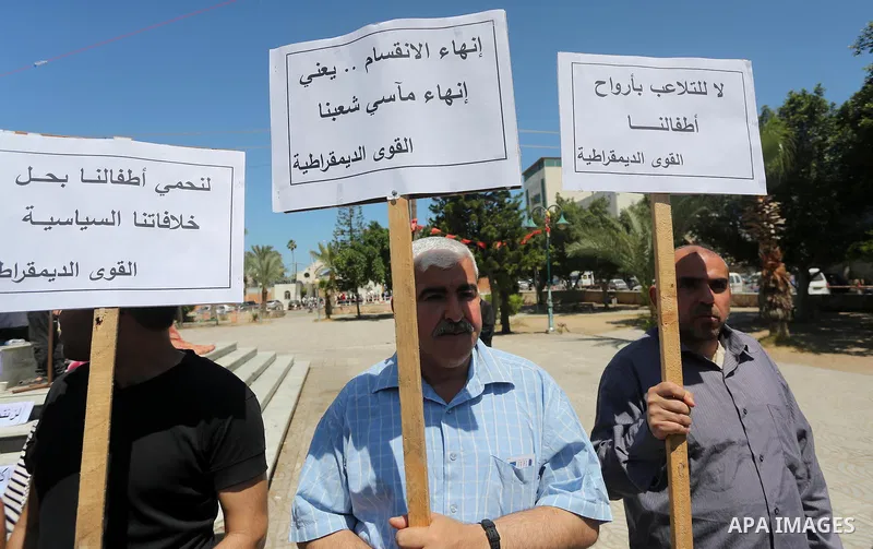 Palestinians hold placards during a protest against a power cut and the Israeli blockade of the Gaza Strip, in Gaza city on May 8, 2016. Photo by Mohammed Asad