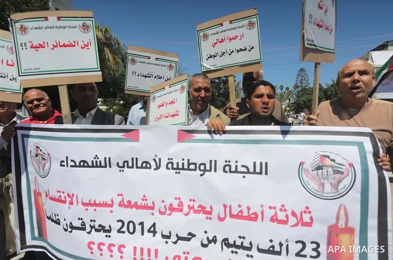 Palestinians hold placards during a protest against a power cut and the Israeli blockade of the Gaza Strip, in Gaza city on May 8, 2016. Photo by Mohammed Asad