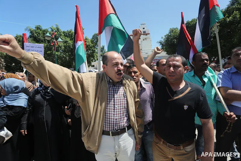 Palestinians hold placards during a protest against a power cut and the Israeli blockade of the Gaza Strip, in Gaza city on May 8, 2016. Photo by Mohammed Asad