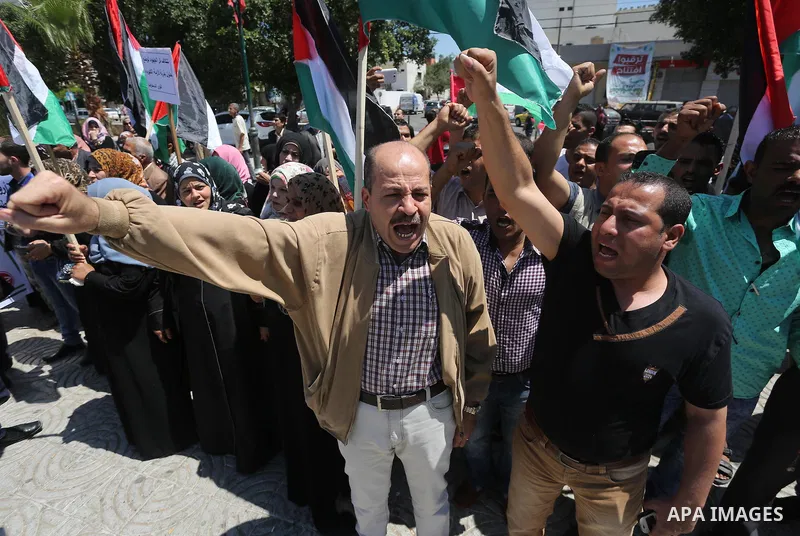 Palestinians hold placards during a protest against a power cut and the Israeli blockade of the Gaza Strip, in Gaza city on May 8, 2016. Photo by Mohammed Asad