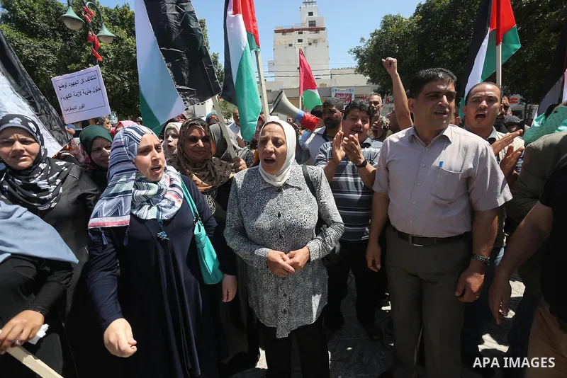 Palestinians hold placards during a protest against a power cut and the Israeli blockade of the Gaza Strip, in Gaza city on May 8, 2016. Photo by Mohammed Asad