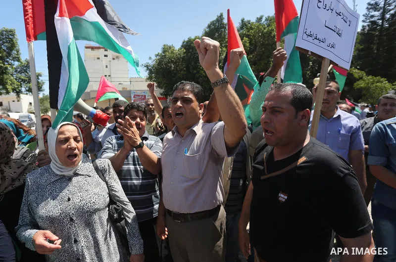 Palestinians hold placards during a protest against a power cut and the Israeli blockade of the Gaza Strip, in Gaza city on May 8, 2016. Photo by Mohammed Asad