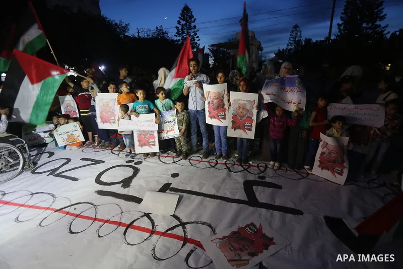 Palestinian children hold placards during a protest demanding for end the siege on Gaza and against the killing of three boys from the al-Hindi family, who died in a fire caused by a candle at the family home in Gaza cit...