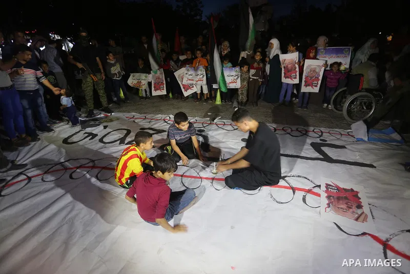 Palestinian children hold placards during a protest demanding for end the siege on Gaza and against the killing of three boys from the al-Hindi family, who died in a fire caused by a candle at the family home in Gaza cit...