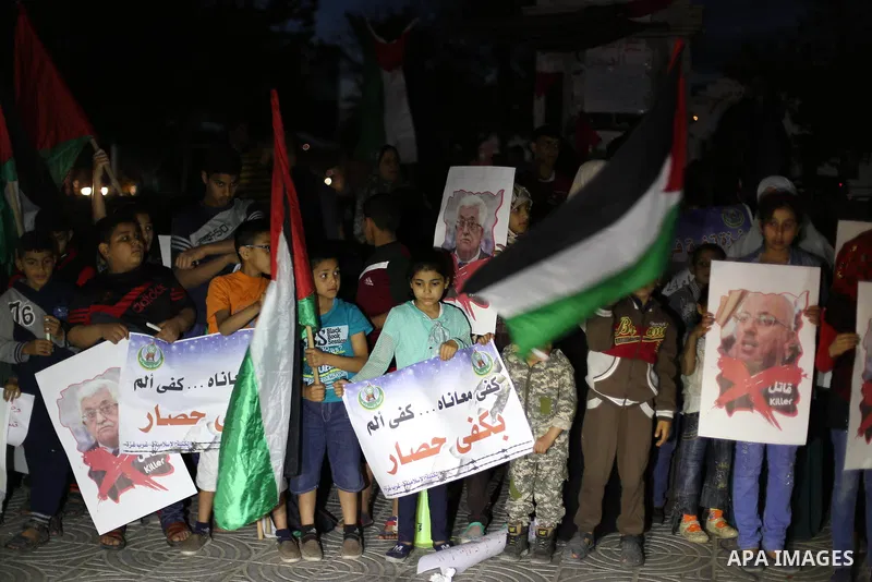 Palestinian children hold placards during a protest demanding for end the siege on Gaza and against the killing of three boys from the al-Hindi family, who died in a fire caused by a candle at the family home in Gaza cit...