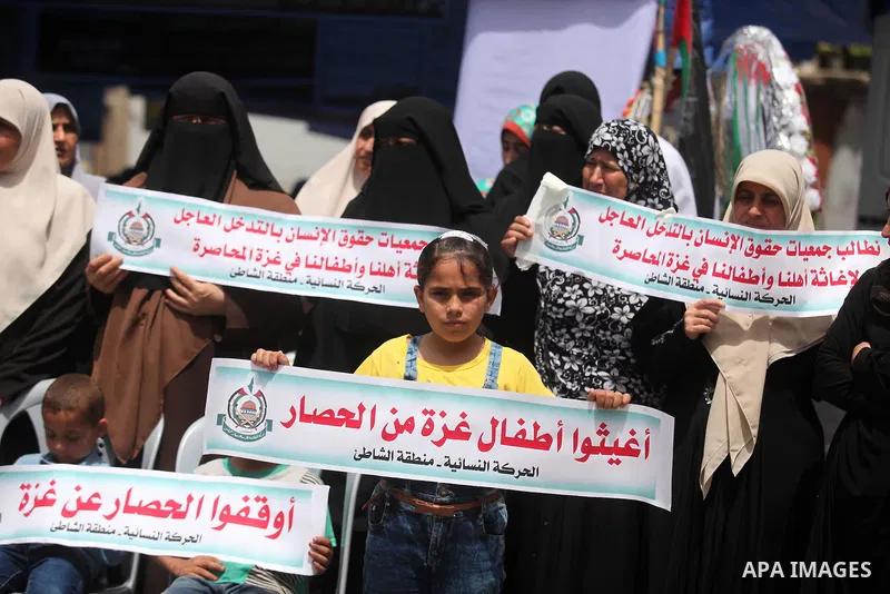 Palestinian children hold placards during a protest against the killing of three boys from the al-Hindi family, who died in a fire caused by a candle at the family home in Gaza city on May 9, 2016. Photo by Ashraf Amra