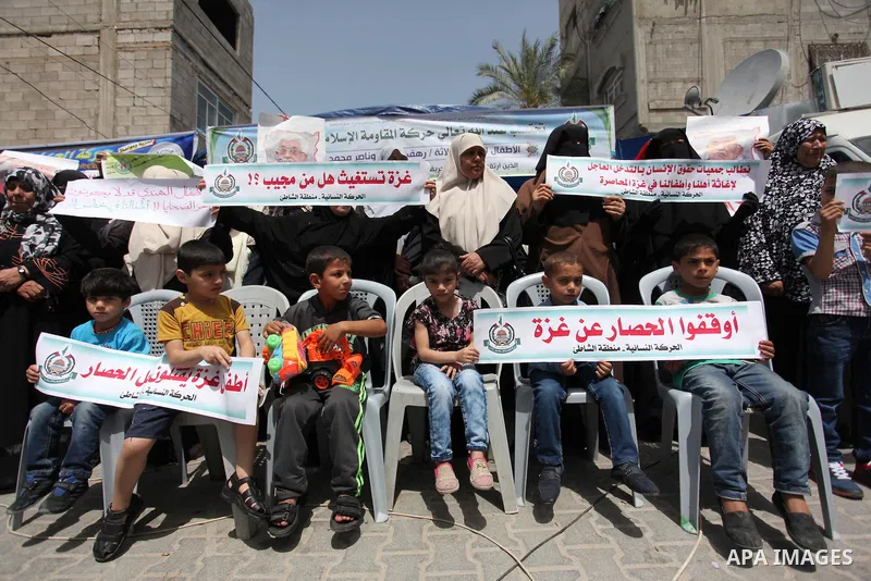 Palestinian children hold placards during a protest against the killing of three boys from the al-Hindi family, who died in a fire caused by a candle at the family home in Gaza city on May 9, 2016. Photo by Ashraf Amra