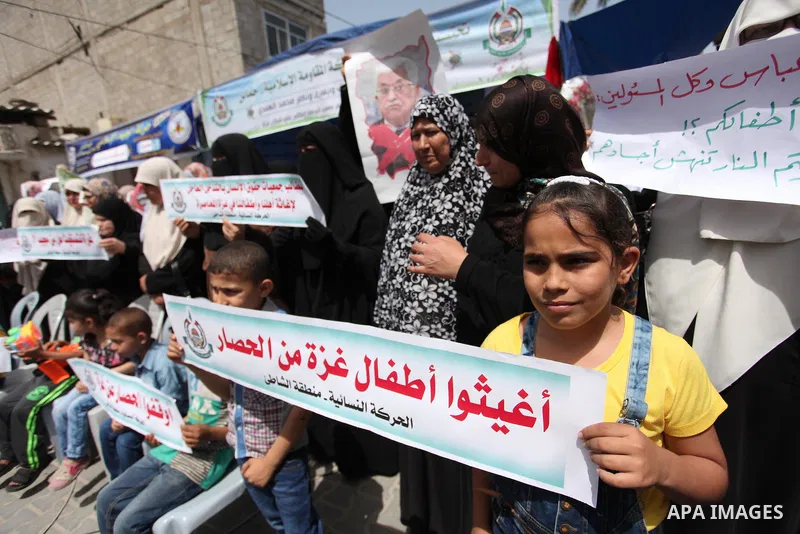 Palestinian children hold placards during a protest against the killing of three boys from the al-Hindi family, who died in a fire caused by a candle at the family home in Gaza city on May 9, 2016. Photo by Ashraf Amra
