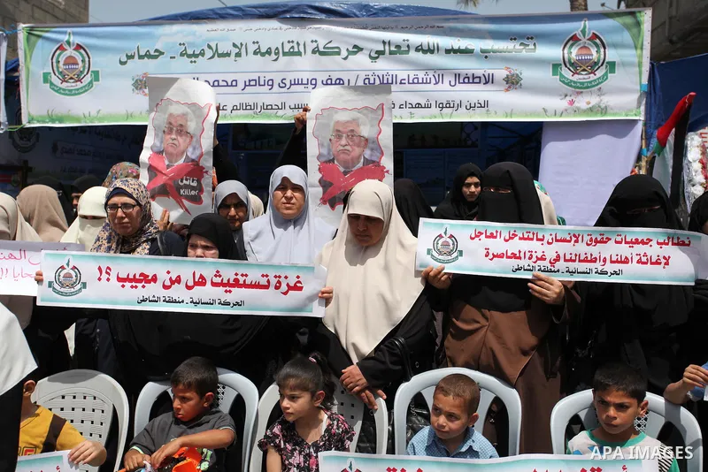 Palestinian children hold placards during a protest against the killing of three boys from the al-Hindi family, who died in a fire caused by a candle at the family home in Gaza city on May 9, 2016. Photo by Ashraf Amra
