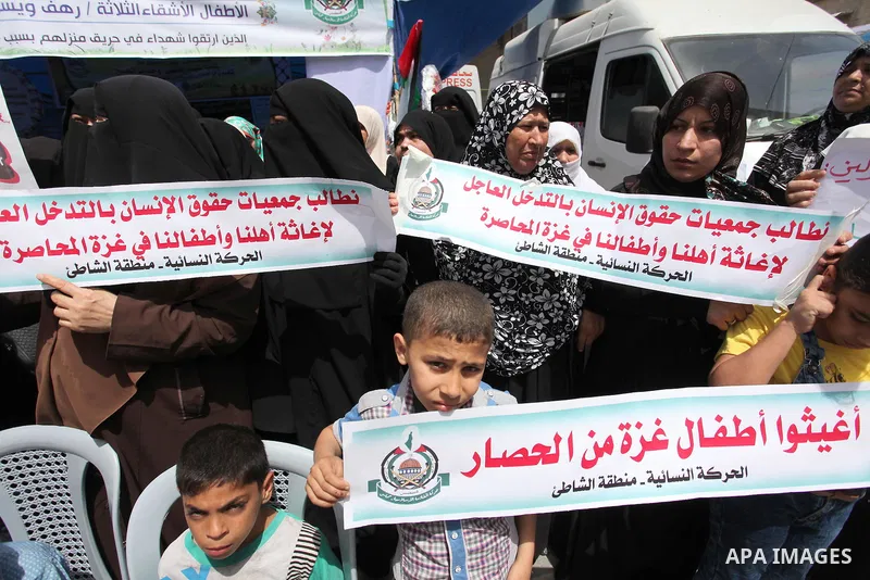 Palestinian children hold placards during a protest against the killing of three boys from the al-Hindi family, who died in a fire caused by a candle at the family home in Gaza city on May 9, 2016. Photo by Ashraf Amra