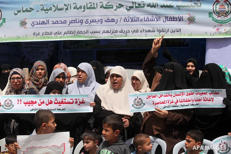 Palestinian children hold placards during a protest against the killing of three boys from the al-Hindi family, who died in a fire caused by a candle at the family home in Gaza city on May 9, 2016. Photo by Ashraf Amra