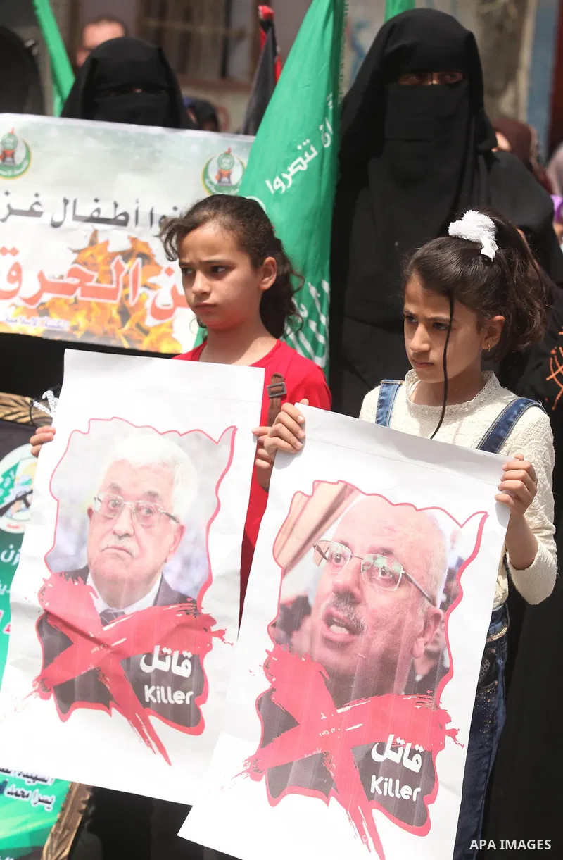 Palestinian children hold placards during a protest against the killing of three boys from the al-Hindi family, who died in a fire caused by a candle at the family home in Gaza city on May 9, 2016. Photo by Ashraf Amra