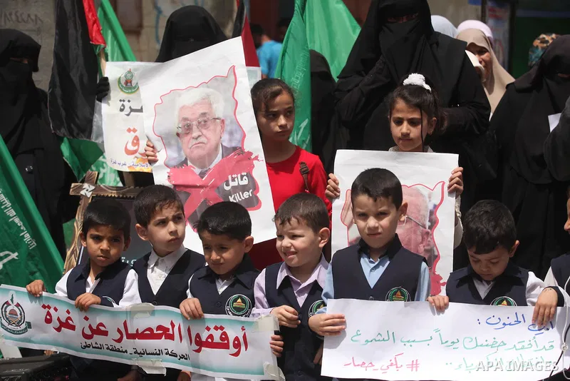 Palestinian children hold placards during a protest against the killing of three boys from the al-Hindi family, who died in a fire caused by a candle at the family home in Gaza city on May 9, 2016. Photo by Ashraf Amra