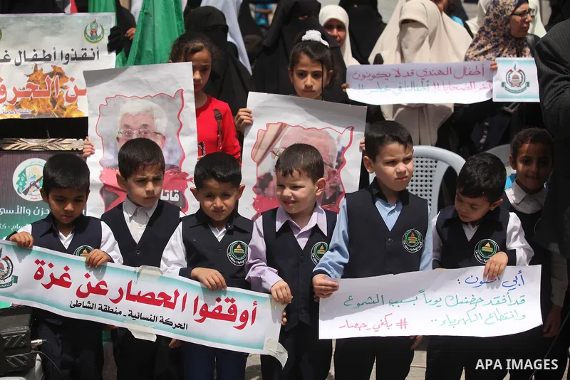 Palestinian children hold placards during a protest against the killing of three boys from the al-Hindi family, who died in a fire caused by a candle at the family home in Gaza city on May 9, 2016. Photo by Ashraf Amra