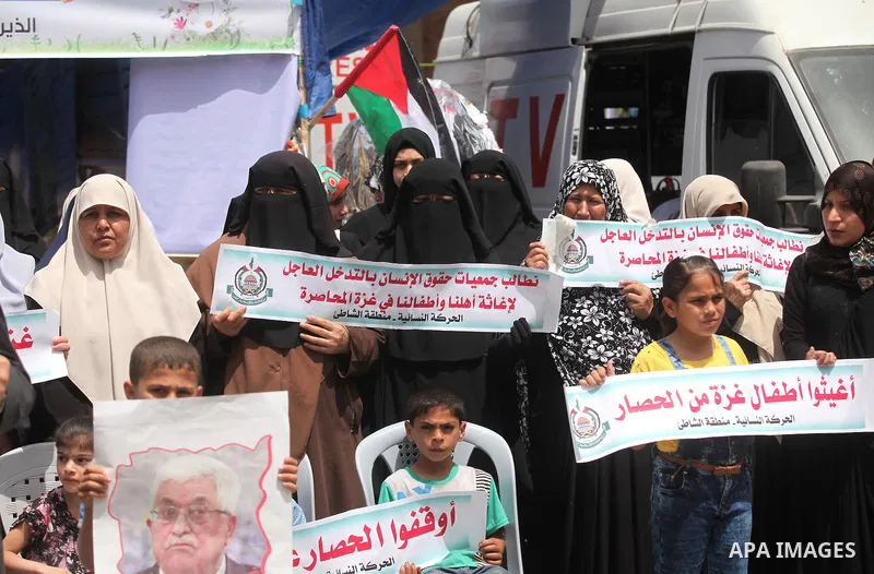 Palestinian children hold placards during a protest against the killing of three boys from the al-Hindi family, who died in a fire caused by a candle at the family home in Gaza city on May 9, 2016. Photo by Ashraf Amra