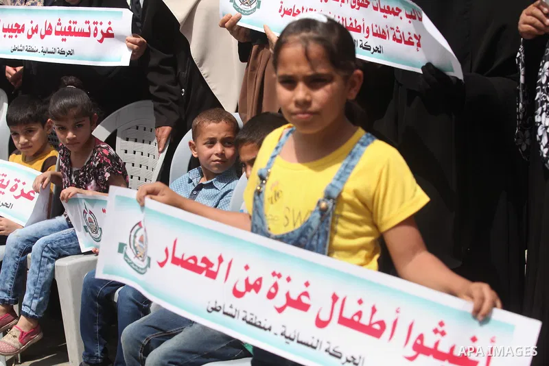 Palestinian children hold placards during a protest against the killing of three boys from the al-Hindi family, who died in a fire caused by a candle at the family home in Gaza city on May 9, 2016. Photo by Ashraf Amra