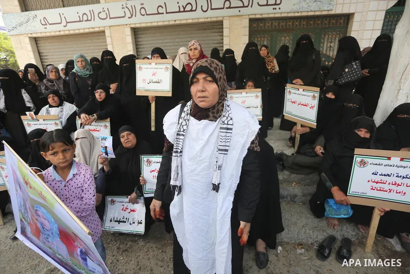 Palestinian families of martyrs, hold banners during a protest to demand their salaries, in Gaza city, on May 10, 2016. Photo by Mohammed Asad