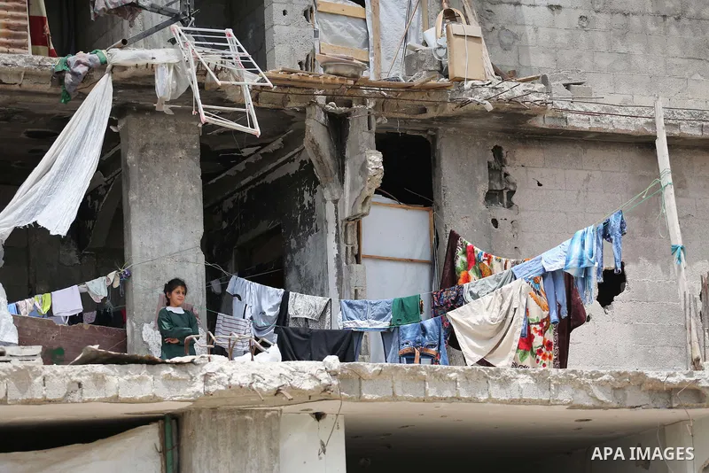 A Palestinian girl stands on a destroyed house while Belgian Foreign Minister Didier Reynders delivers a speech in the eastern Gaza City Shujaiya neighbourhood, which was destroyed during the 50-day war between Israel an...