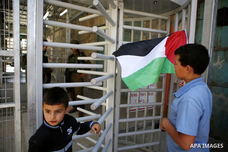 A Palestinian boy holds a national flag during a protest against the closure of Shuhada street to Palestinians in the West Bank city of Hebron on May 12, 2016. Photo by Wisam Hashlamoun