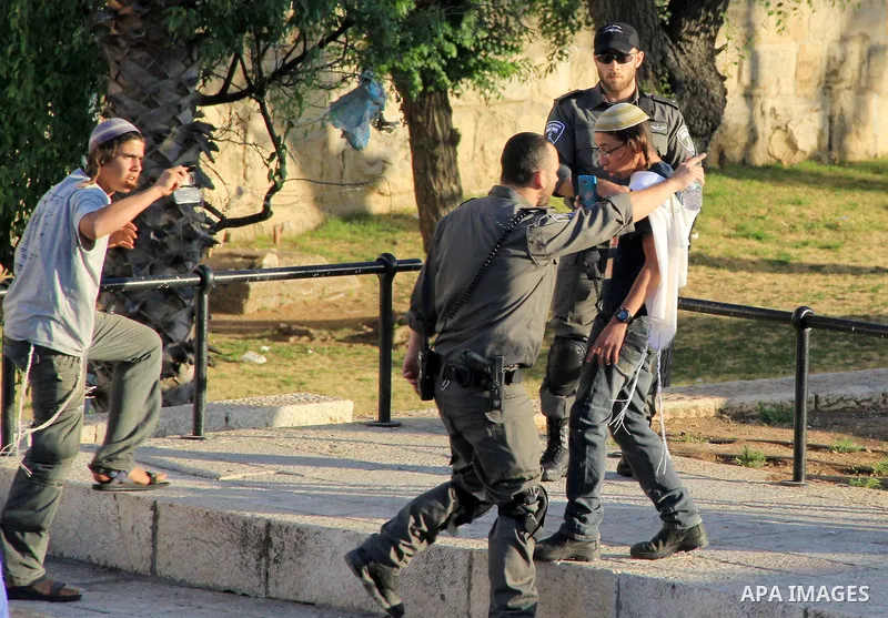 A member of Israeli security forces argues in front of Jewish settlers in front of the Damascus Gate, a main entrance to Jerusalem's Old City on May 12, 2016. Photo by Mahfouz Abu Turk