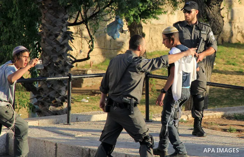 A member of Israeli security forces argues in front of Jewish settlers in front of the Damascus Gate, a main entrance to Jerusalem's Old City on May 12, 2016. Photo by Mahfouz Abu Turk