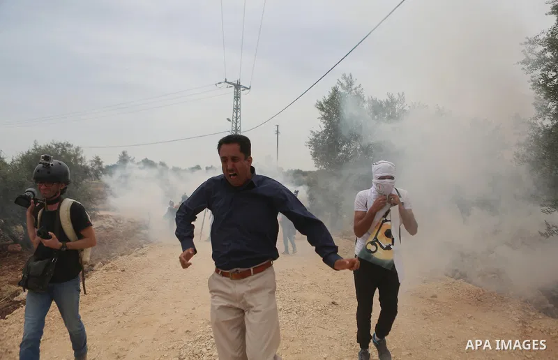 Palestinian protesters run for cover from tear gas fired by Israeli troops during clashes at a protest ahead of Nakba day, in the West Bank village of Bilin near Ramallah May 13, 2016. Photo by Shadi Hatem