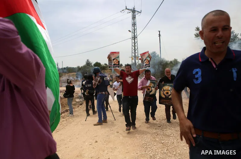 Palestinian protesters run for cover from tear gas fired by Israeli troops during clashes at a protest ahead of Nakba day, in the West Bank village of Bilin near Ramallah May 13, 2016. Photo by Shadi Hatem