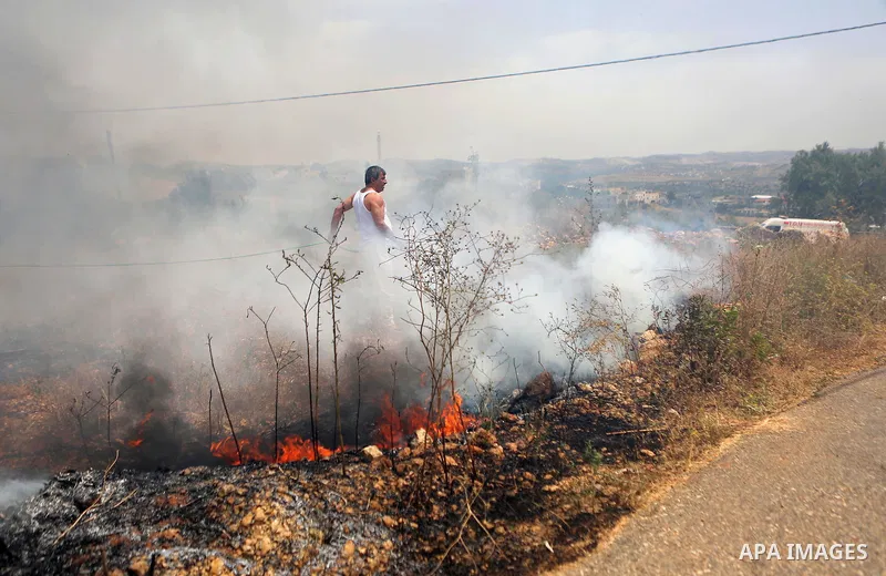 A Palestinian protester uses a water hose as he tries to extinguish a fire caused by tear gas fired by Israeli troops during clashes at a protest ahead of Nakba day, in the West Bank village of Bilin near Ramallah May 13...