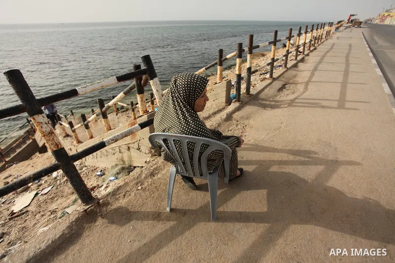 A Palestinian woman sits in front of the beach at the al-Shati refugee camp in Gaza City on May 14, 2016. Photo by Ashraf Amra