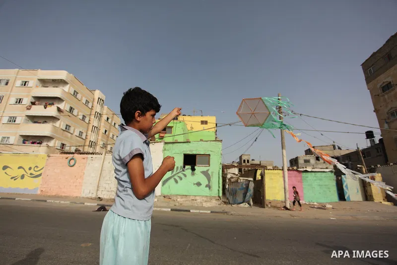 A Palestinian boy flies a kite on at the al-Shati refugee camp in Gaza City on May 14, 2016. Photo by Ashraf Amra
