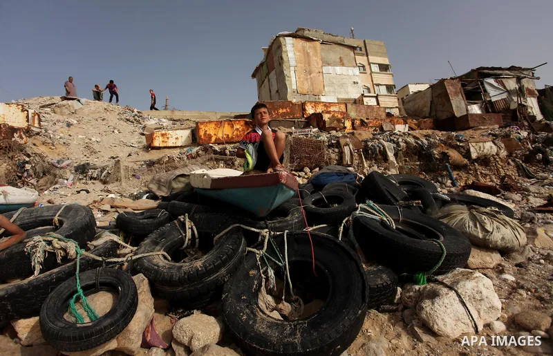 A Palestinian boy sits on a boat on the beach at the al-Shati refugee camp in Gaza City on May 14, 2016. Photo by Ashraf Amra