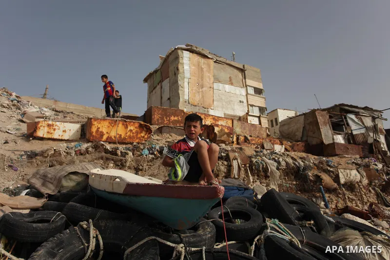 A Palestinian boy sits on a boat on the beach at the al-Shati refugee camp in Gaza City on May 14, 2016. Photo by Ashraf Amra