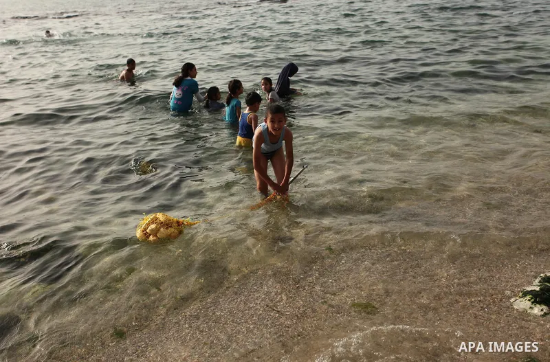 Palestinian children play in the water on the beach at the al-Shati refugee camp in Gaza City on May 14, 2016. Photo by Ashraf Amra