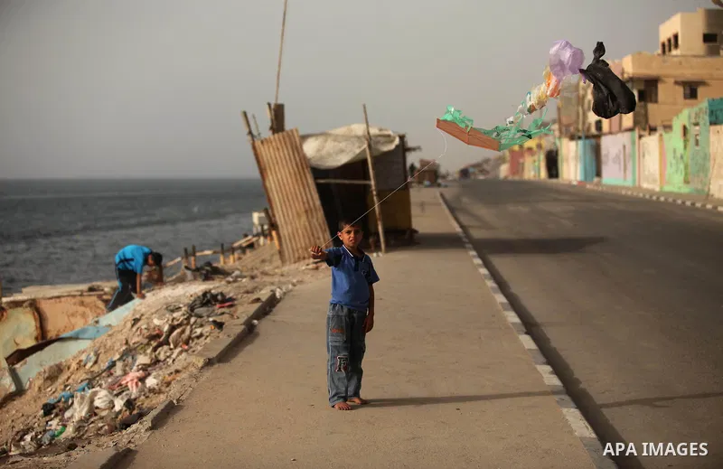 A Palestinian boy flies a kite on at the al-Shati refugee camp in Gaza City on May 14, 2016. Photo by Ashraf Amra