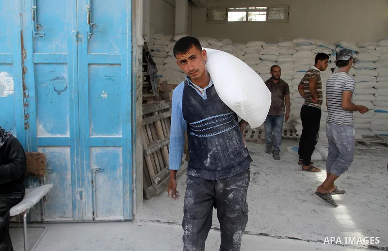 A Palestinian man carries a bag of flour to distribute to families, at an aid distribution centre of the United Nations Relief and Works Agency (UNRWA) in the southern Gaza Strip town of Khan Younis on May 15, 2016, on t...
