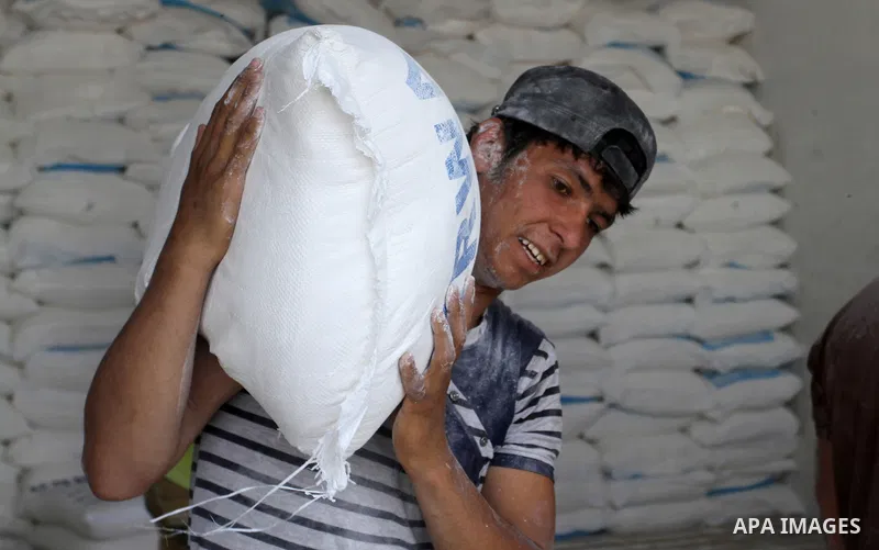 A Palestinian man carries a bag of flour to distribute to families, at an aid distribution centre of the United Nations Relief and Works Agency (UNRWA) in the southern Gaza Strip town of Khan Younis on May 15, 2016, on t...