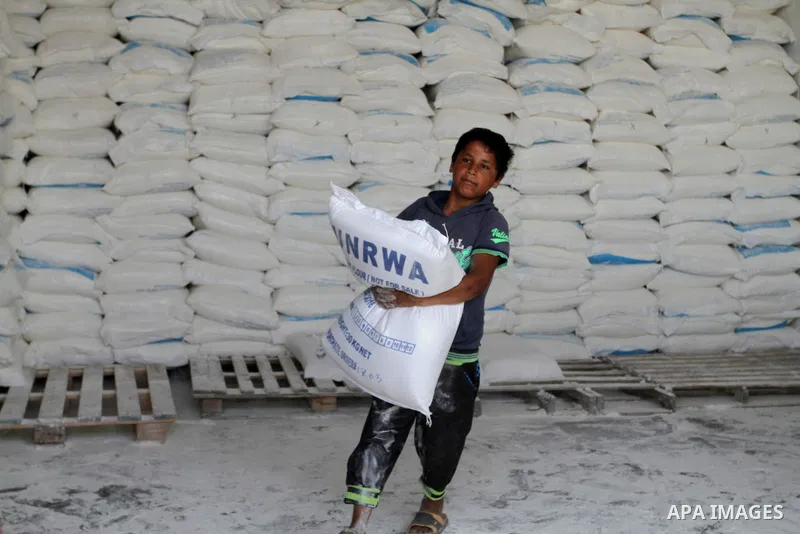 A Palestinian boy carries a bag of flour to distribute to families, at an aid distribution centre of the United Nations Relief and Works Agency (UNRWA) in the southern Gaza Strip town of Khan Younis on May 15, 2016, on t...