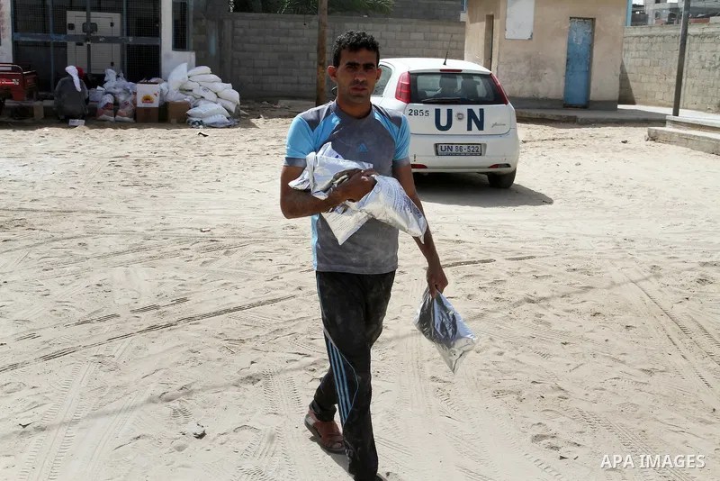 A Palestinian man carries a bag of flour to distribute to families, at an aid distribution centre of the United Nations Relief and Works Agency (UNRWA) in the southern Gaza Strip town of Khan Younis on May 15, 2016, on t...