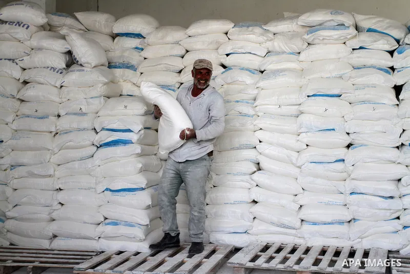 A Palestinian man carries a bag of flour to distribute to families, at an aid distribution centre of the United Nations Relief and Works Agency (UNRWA) in the southern Gaza Strip town of Khan Younis on May 15, 2016, on t...