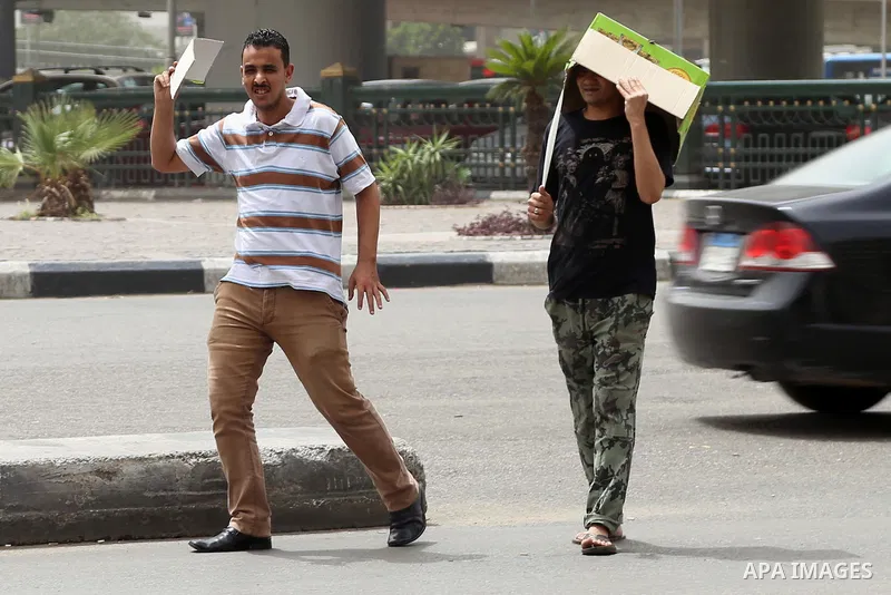 Egyptian men cover themselve from the sun during a sweltering heat wave, in Cairo, Egypt, on May 15, 2016. Photo by Amr Sayed