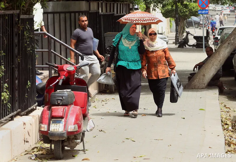 Egyptian women use umbrella to cover themselve from the sun during a sweltering heat wave, in Cairo, Egypt, on May 15, 2016. Photo by Amr Sayed