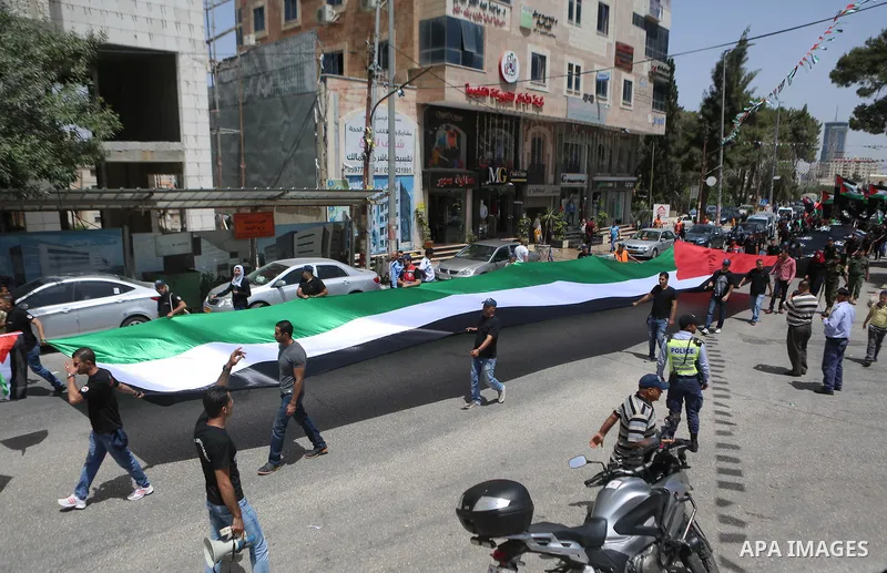 Palestinians hold a flag during in a procession on the 68th anniversary of the "Nakba" in the West Bank city of Ramallah on May 15, 2016. "Nakba" means in Arabic "catastrophe" in reference to the birth of the state of Is...