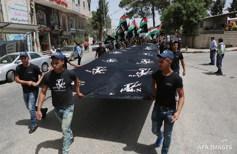 Palestinians hold a flag during in a procession on the 68th anniversary of the "Nakba" in the West Bank city of Ramallah on May 15, 2016. "Nakba" means in Arabic "catastrophe" in reference to the birth of the state of Is...