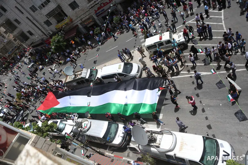 Palestinians hold a flag during in a procession on the 68th anniversary of the "Nakba" in the West Bank city of Ramallah on May 15, 2016. "Nakba" means in Arabic "catastrophe" in reference to the birth of the state of Is...